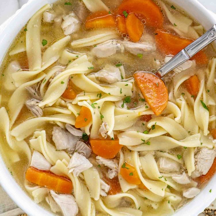 a serving of leftover turkey noodle soup in a white bowl.