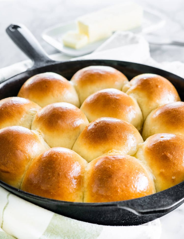 side shot of freshly baked quick yeast dinner rolls in a skillet brushed with butter